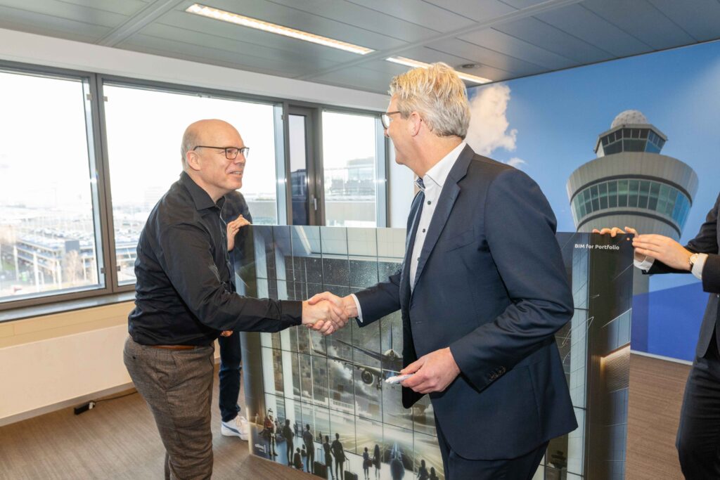 Peter Luske (Schiphol Group) en Cees Versteeg (Allinq Digital) feliciteren elkaar met de samenwerking